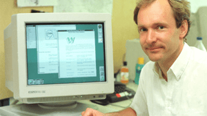 A photo of Sir Tim Berners Lee in front of a computer showing the first version of the web the photo is clearly from the 90s based on the size of the computer and Sir Tim's age!