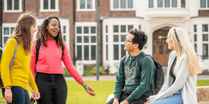 Four diverse group of university students talking outside on campus