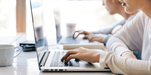 A woman looking at a laptop screen with her hand on the keyboard.