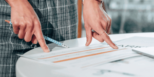 A person pointing at documents on the table.