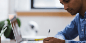 A business man working, writing notes down on a notebook with a pen. 