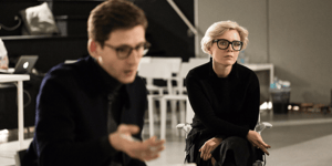 Two people sat next to each other looking seriously at something not pictured. 