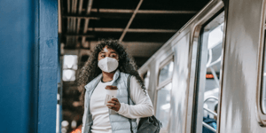 Woman wearing a mask walking of the train at the train station.