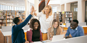 A diverse group of people in a library celebrating success, and two people high-fiving each other. 