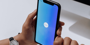 A hand holding an iPhone with the Canva app open.