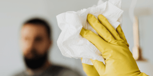 A man cleaning a mirror with yellow globes and a white tissue.