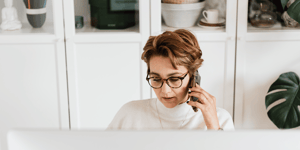 A business woman on the phone looking at her laptop screen.
