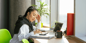 A woman sat on a desk using a calculator.