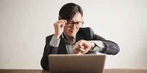 A stressed man looking at the watch on his hand.