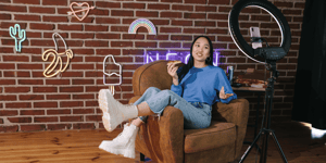 A content creator influencer sat on a sofa talking in front of a camera (not pictured)