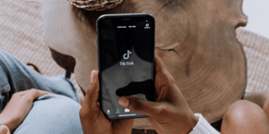 Person holding an iPhone with the TikTok app open, showing the TikTok logo.